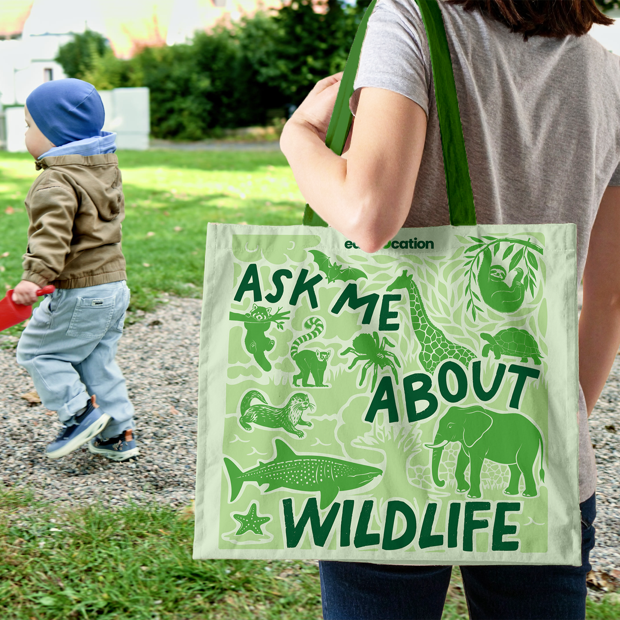 Person holding a tote bag with animal illustrations and text in an outdoor setting