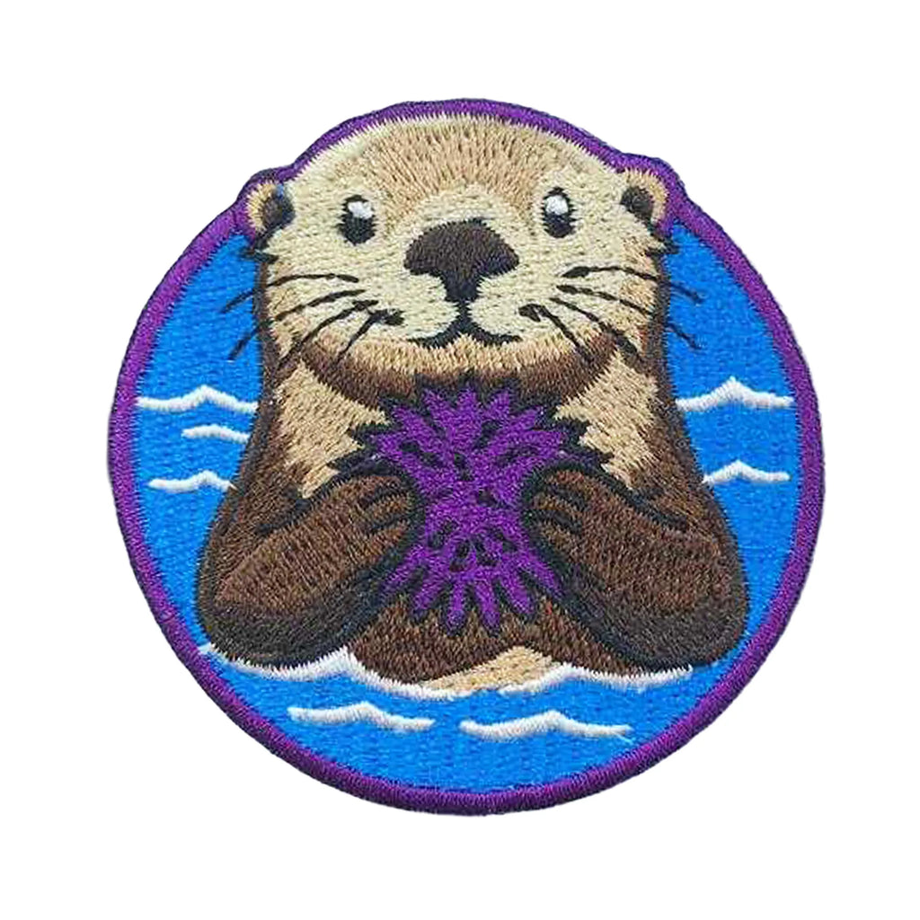 Embroidered patch of an otter holding a purple sea urchin with a blue background