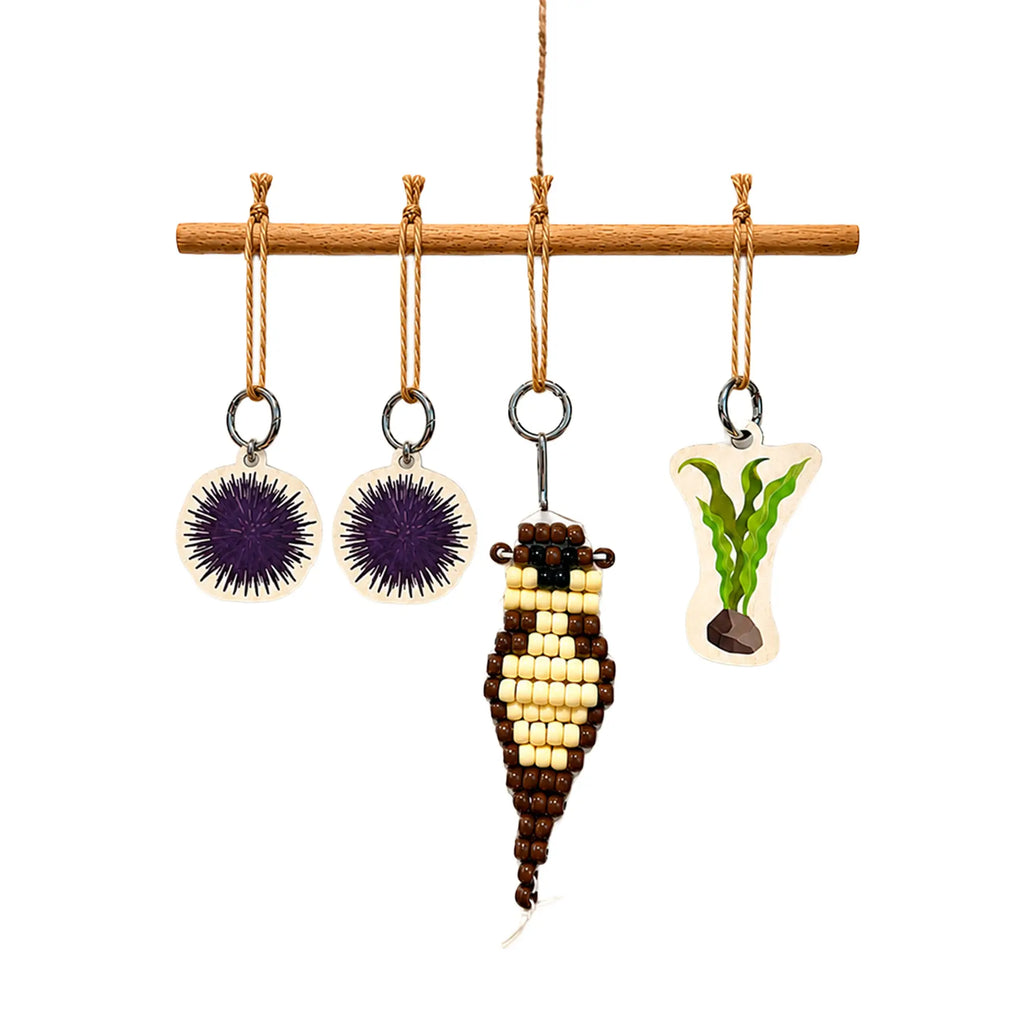 Set of hanging Sea Otter ornaments on a wooden rod with a white background